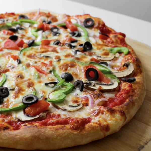 A whole vegetarian pizza with green peppers, black olives, mushrooms, tomatoes, and onions.