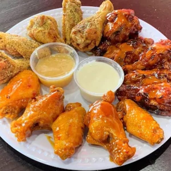 A platter of House Of Wings chicken wings in various flavors, with two dipping sauces.